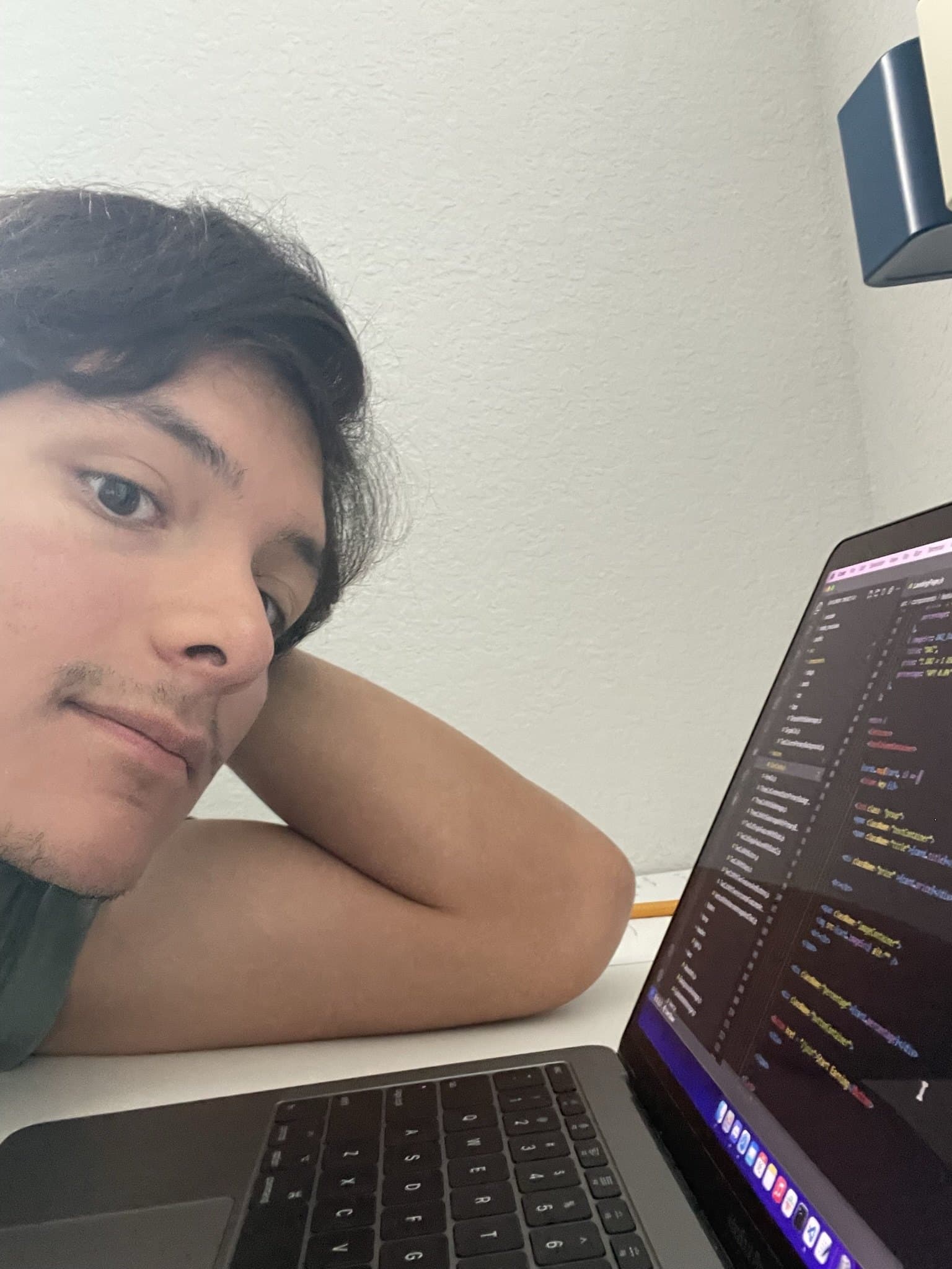 Emmanuel Mendieta resting his head beside a laptop full of code